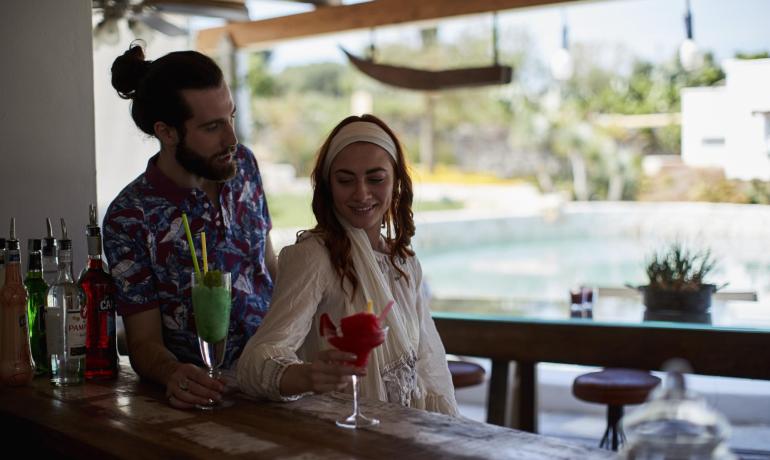 Couple heureux dégustant des cocktails colorés dans un bar d'été en plein air.